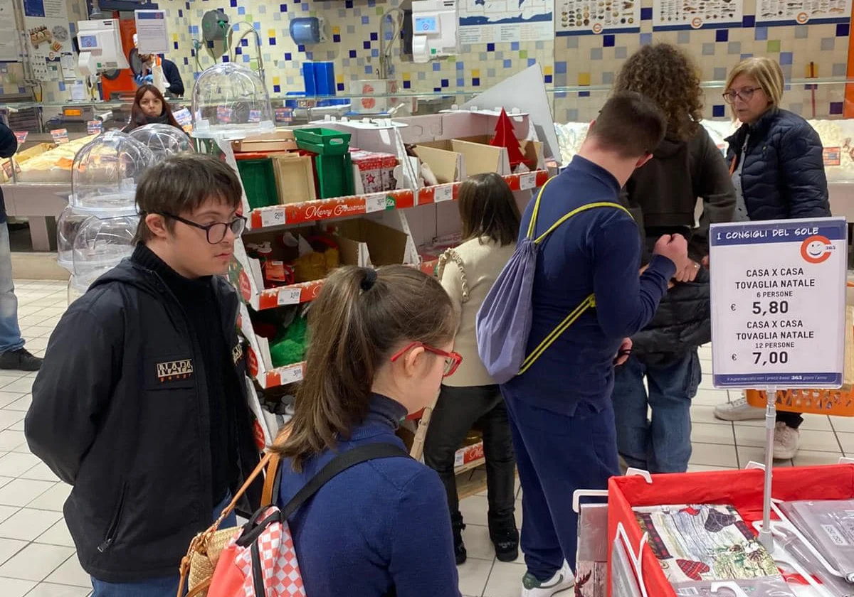 Un gruppo di ragazzi sceglie articoli natalizi tra gli scaffali di un supermercato.
