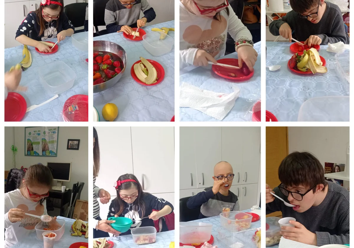 Alcuni ragazzi tagliano banane e fragole a tavola, durante la preparazione di una macedonia.