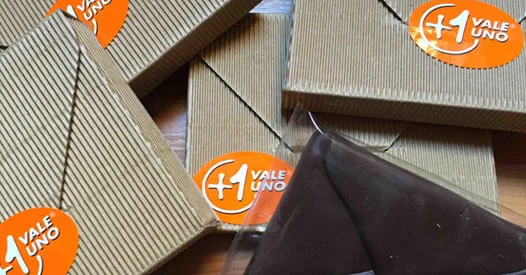 Tavolette di cioccolato equosolidale confezionate, con adesivi arancioni "+1 vale uno".
