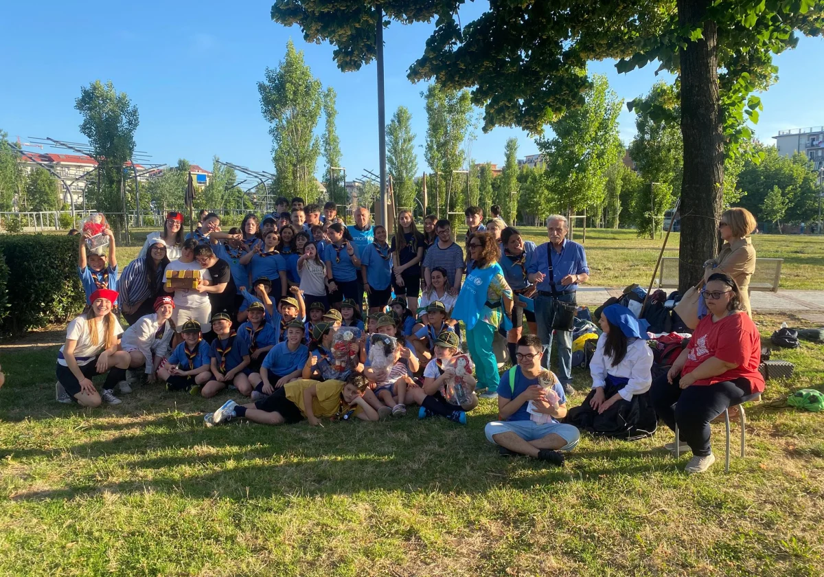 Un grande gruppo, tra cui ragazzi e uno scout in uniforme, in posa in un parco.