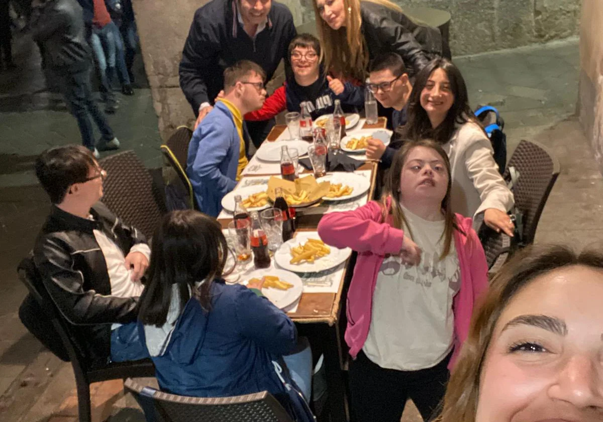 Un gruppo seduto a un tavolo all'aperto durante una cena, in un selfie di gruppo.
