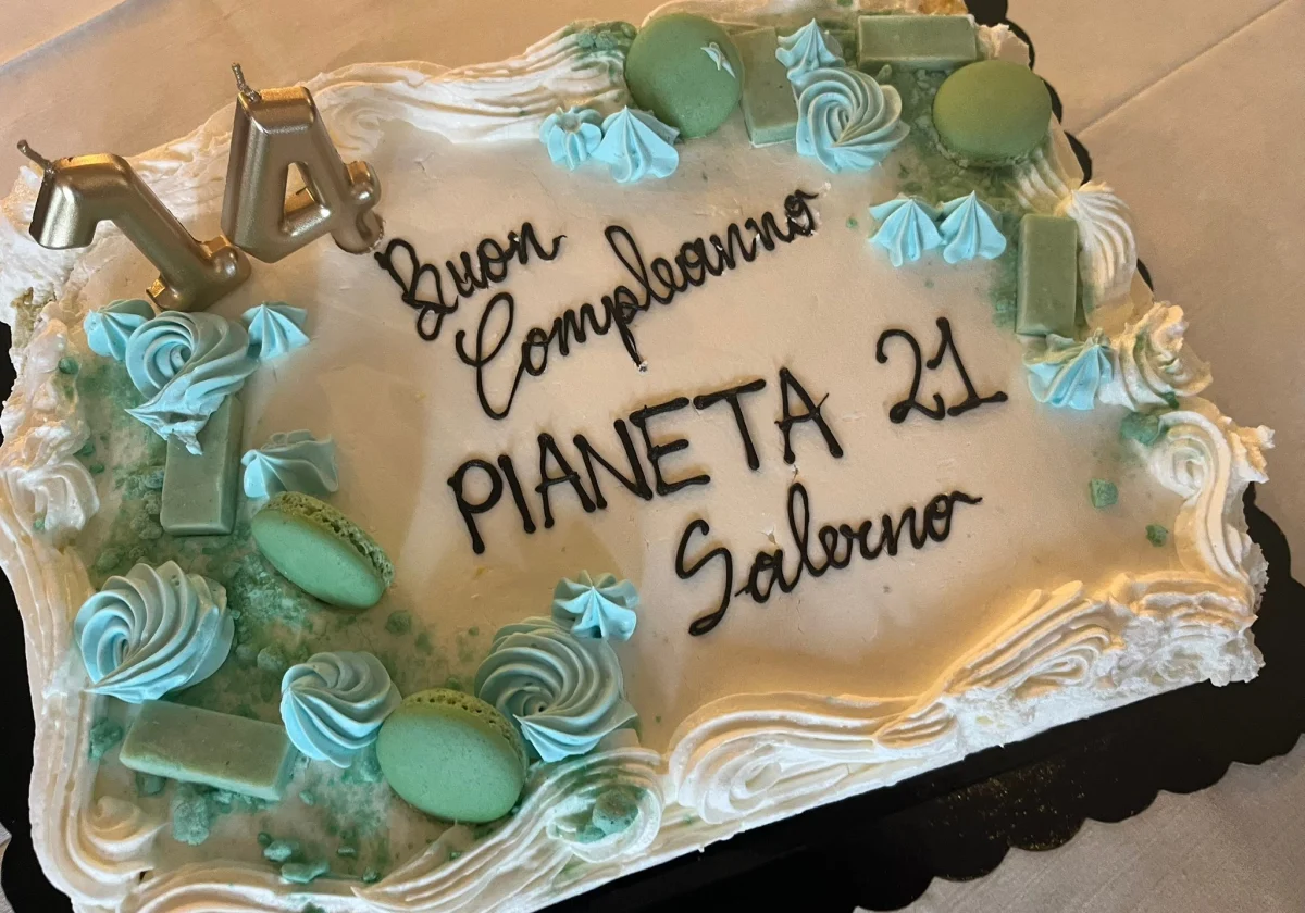 Torta con la scritta "Buon Compleanno Pianeta 21 Salerno" e la candelina a forma di "14".