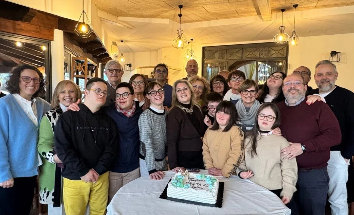 Un gruppo di soci e volontari di Pianeta 21 riuniti per una festa di compleanno, con una torta al centro del tavolo.