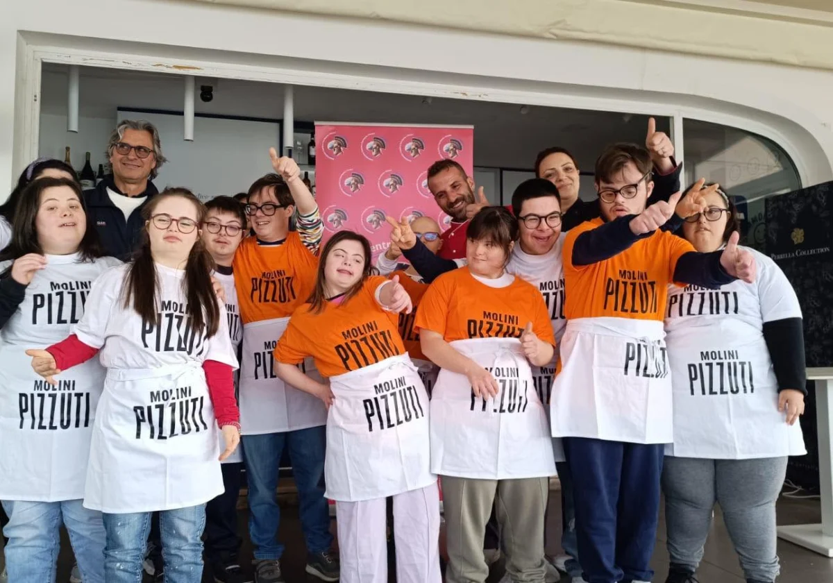 Un gruppo con grembiuli da pizzaiolo durante un laboratorio di panificazione.